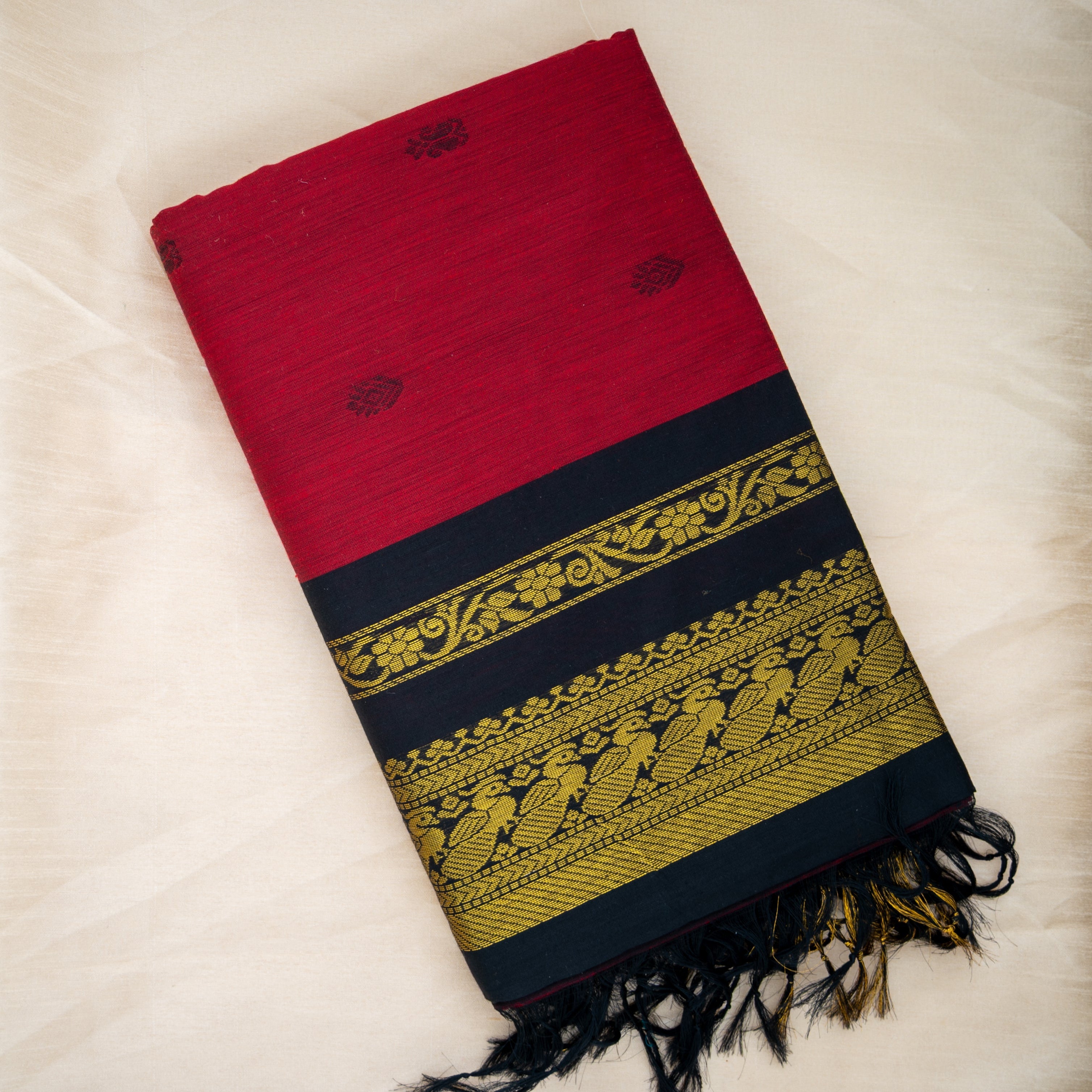 Red, black, and gold woven fabric with intricate patterns on a light background